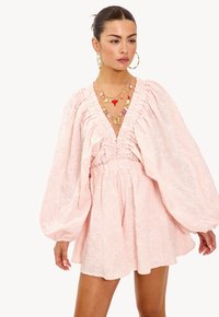 Roze geborduurde jurk met een diepe V-hals, puffed mouwen en een geraffineerde taille. Beschikt over bloempatronen en een ontspannen silhouet.