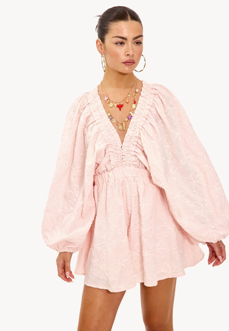 Roze geborduurde jurk met een diepe V-hals, puffed mouwen en een geraffineerde taille. Beschikt over bloempatronen en een ontspannen silhouet.