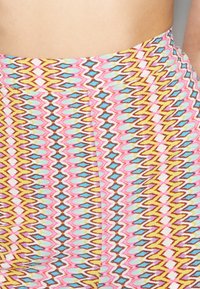 Mönstrade höga leggings i pastellfärger som rosa, blå, gul och brun, med ett vågigt geometriskt mönster och texturerad tyg.