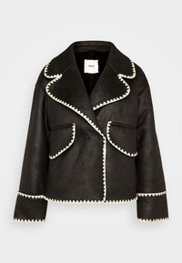 Zwarte faux leren jas met een brede kraag, witte zigzagstiksel langs de randen en twee voorzakken.