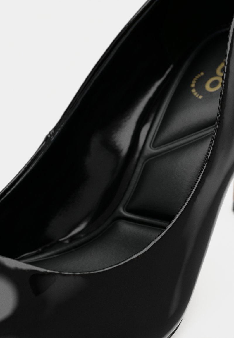 Schwarze Lackleder-Pumps mit spitz zulaufender Zehenpartie und gepolstertem Innenraum, ausgestattet mit einer glänzenden Oberfläche und minimalistischem Design.