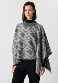 Szary poncho z dużym, kontrastowym wzorem logo, wykonane z miękkiego materiału o delikatnej strukturze. Wysoki kołnierz i luźne rękawy.