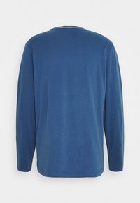 Langærmet T-shirt med rund hals i ensfarvet blå. Fremstillet af blødt stof med en glat overflade. Har et enkelt design og lige snit.