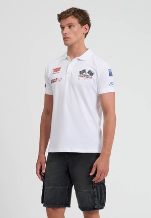 Polo shirt bianco con colletto, maniche corte e vari accenti ricamati tra cui loghi e strisce colorate nella zona del petto.
