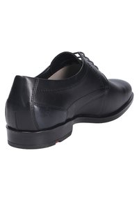 Schwarze Lederdressschuhe mit glatter Textur, Schnürdesign, abgerundeter Zehenpartie und einem soliden schwarzen Absatz mit rotem Akzent an der Sohle.
