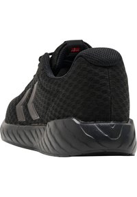 Chaussure de sport noire avec dessus en tissu texturé, rayures chevron grises sur le côté, col rembourré et semelle épaisse sculptée vue de dos.