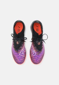 Baskets de sport noires avec un dessus texturé en dégradé violet et orange, dotées de lacets noirs et d'accents de logo bien visibles.