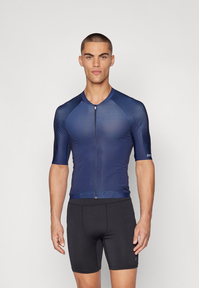 Marineblå sykkeltrøye med korte ermer, med glidelås foran og tettsittende design, sammen med svarte sykkelshorts. Jevn tekstur.
