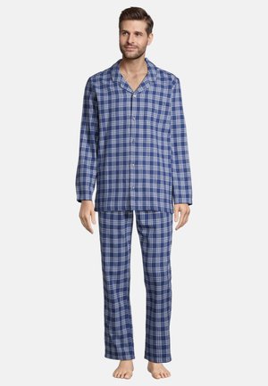 Mand stående barfodet iført blå og hvide ternede pyjamas med knapper og lange ærmer samt matchende bukser mod hvid baggrund.