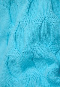 Hellblauer Strickstoff mit einem strukturierten Muster aus Rauten und abwechselnden glatten und gerippten Bereichen. Weiches Material.