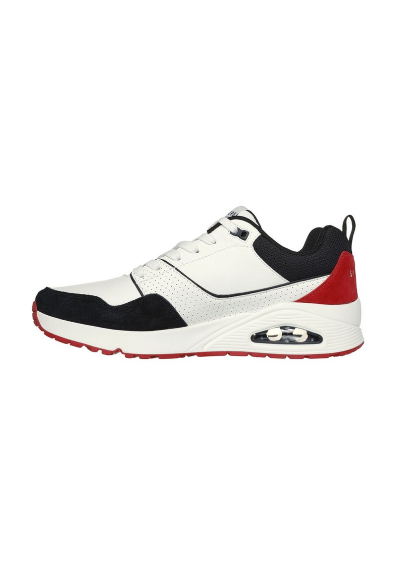 Sneaker blanc avec accents noirs et rouges, présentant une tige en cuir lisse, une coque de tête en daim, un design perforé et un amorti à air visible.