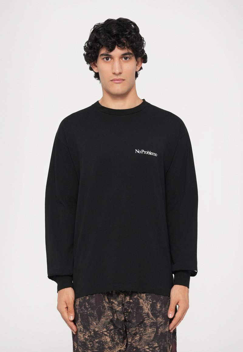 Sort langærmet T-shirt med rund hals og hvid "No Problemo" tekst på venstre bryst, lavet af blødt bomuldsstof.