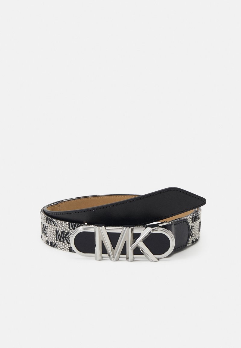 Ceinture noire et argentée avec motif répété "MK" et grande boucle argentée "MK", posée enroulée sur un fond blanc uni.