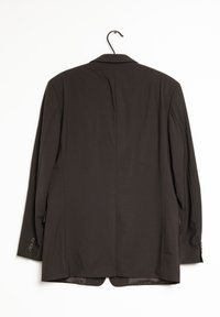 Blazer nero appeso a un gancio, con una fessura singola sul retro, due tasche laterali e polsini con bottoni sulle maniche.