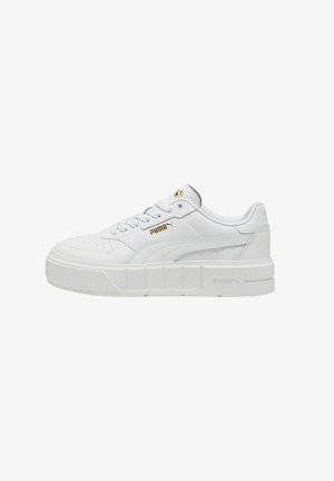 Biały niski sneaker Puma z grubą podeszwą, sznurowaniem z przodu i złotym logo Puma z boku i na języku.