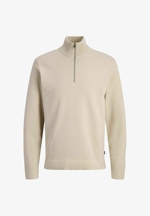 Bézs színű, hosszú ujjú kötött pulóver magas gallérral és elöl fél cipzáras záródással.