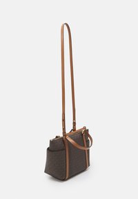 Borsa a spalla marrone con motivo e rifiniture in pelle beige. Presenta una tracolla lunga e due tasche esterne. Chiusura con zip in cima.