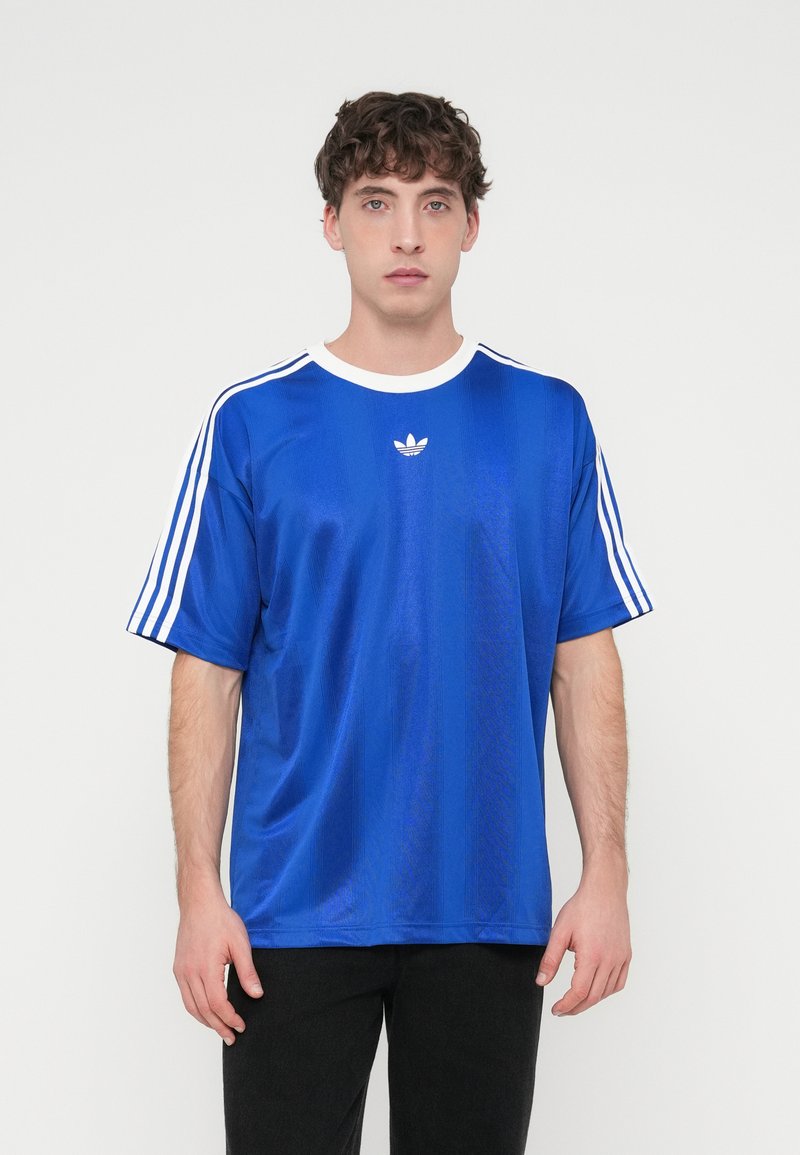 Blaues Polyester-T-Shirt mit weißem Kragen und drei weißen Streifen auf jeder Schulter. Verfügt über ein kleines weißes Logo auf der Brust.