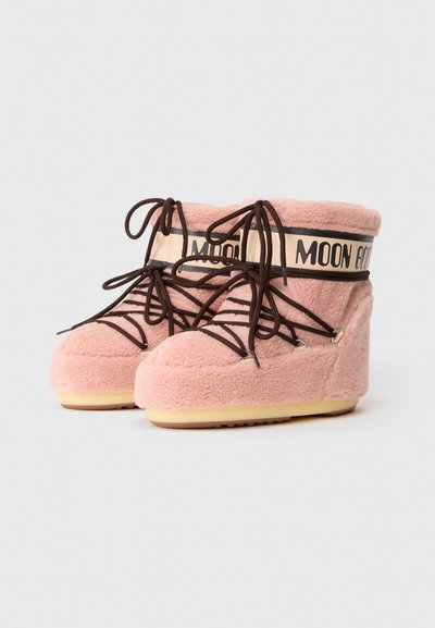 Różowe, ocieplane buty Moon Boots z brązowymi sznurówkami i beżowymi gumowymi podeszwami, z odblaskowym paskiem z czarnym napisem wokół kostki.