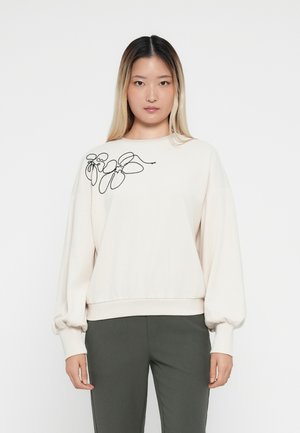 Helles beige Sweatshirt mit schwarzer floralem Stickerei auf der linken Schulter, ausgestattet mit langen, voluminösen Ärmeln und einem gerippten Saum.