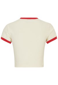 Camiseta corta de manga corta en tejido crema con cuello y dobladillos de mangas de canalé rojo, textura suave y diseño minimalista.