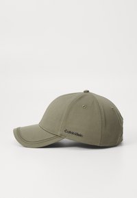 Olivengrønn baseballcap laget av blandingsmateriale, med buet skjerm og brodert "Calvin Klein"-logo på siden.