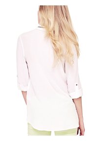Chemise blanche légère avec des manches retroussées et des détails de boutons. Elle présente un ourlet droit et une texture lisse.