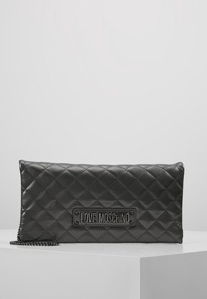 Sort quiltet læder Love Moschino clutch med kædestrop vist på hvid overflade mod grå baggrund.