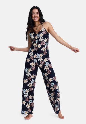 Floral-Jumpsuit mit marineblauem Hintergrund und großen mehrfarbigen Blumen. Es hat dünne Träger und weite Hosenbeine. Leichter Stoff.