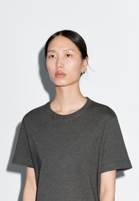 T-shirt grigio a maniche corte realizzato in morbido cotone misto. Presenta un collo rotondo e una vestibilità rilassata. Design semplice senza motivi visibili.