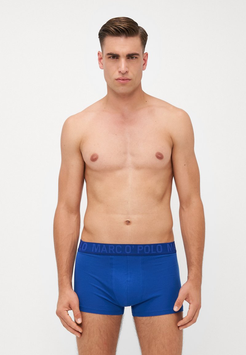 Menns blå boxershorts med en mørkeblå elastisk midjebånd med "MARCO O' POLO" logo, laget av et glatt, stretchy stoff.
