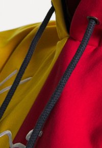 Felpa con cappuccio con sezioni gialle e rosse, dotata di spessi lacci neri e dettagli ricamati sulla parte frontale.