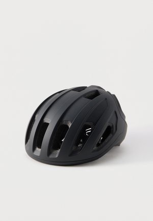 Casque de vélo noir mat avec plusieurs ouvertures de ventilation et un design profilé reposant sur une surface blanche unie.