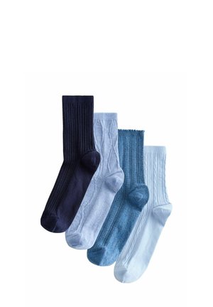 Four pairs of ribbed and cable-knit socks in shades of navy, light blue, denim blue, and white, arranged overlapping on a white background.