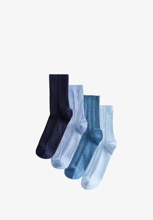 Cuatro pares de calcetines acanalados y de punto trenzado en tonos azul marino, azul claro, azul denim y blanco, dispuestos superpuestos sobre un fondo blanco.