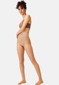 Set di bralette e culotte ad alta vita color nude, realizzato in tessuto trasparente ed elasticizzato con una texture liscia e un design minimalista.