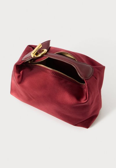 Rode satijnen tas met een gestructureerde vorm, voorzien van een gouden rits en hardware. De tas heeft een platte bodem en een korte handgreep.