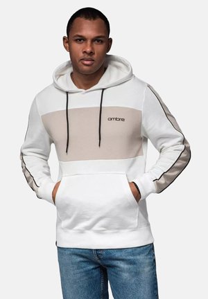 Sudadera con capucha blanca con bloque de color beige, cordones negros y acentos laterales. Cuenta con un bolsillo canguro y un logo en el pecho.