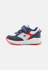 Scarpe da ginnastica blu navy e bianche con accenti rossi, tomaia in rete, cinturino a strappo, collo imbottito e suola in gomma con motivi di grip.