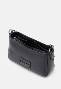 Sac à main en similicuir noir avec une forme rectangulaire, doté d'un patch logo sur le devant, de deux compartiments zippés et d'accents métalliques argentés.