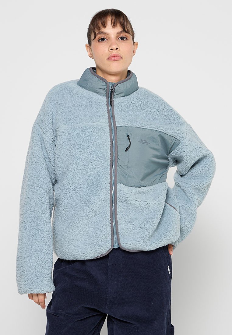 Helle blaue Fleecejacke mit einem Reißverschluss vorne, grauen Akzenten und einer Brusttasche. Weicher Stoff mit hohem Kragen und lockerer Passform.