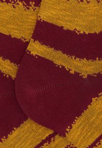 Calze lavorate a maglia con strisce color bordeaux e gialle, caratterizzate da una finitura testurizzata. Il design include un polsino liscio e punta rinforzata.