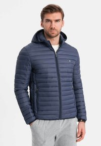 Granatowa puchowa kurtka z kapturem, pikowany wzór, zamek błyskawiczny z przodu oraz dwie boczne kieszenie. Materiał wydaje się gładki i lekki.