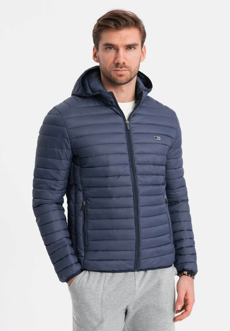 Granatowa puchowa kurtka z kapturem, pikowany wzór, zamek błyskawiczny z przodu oraz dwie boczne kieszenie. Materiał wydaje się gładki i lekki.