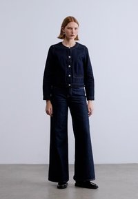 Σκούρο denim μπουφάν με ασημένια κουμπιά, συνδυασμένο με παντελόνι wide-leg από σκούρο denim. Λεπτή υφή και καλόγουστο σχέδιο με καθαρές γραμμές.