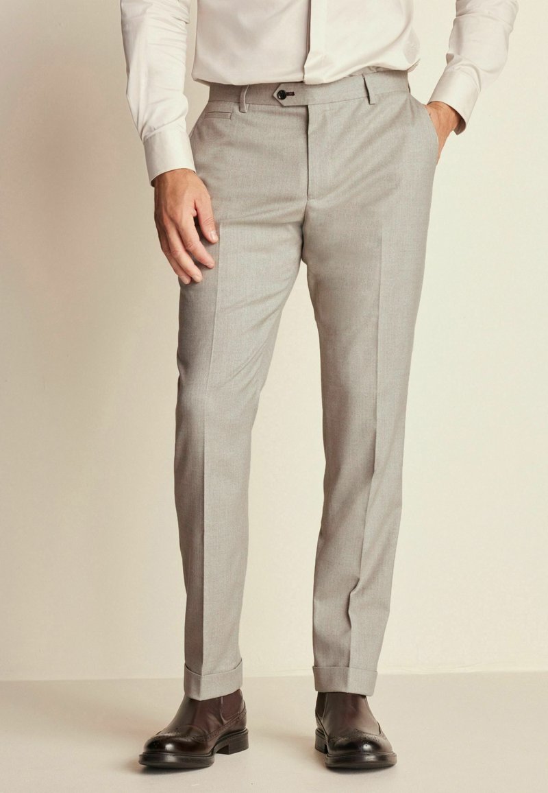 Pantaloni gri croiți dintr-un material texturat, cu fața netedă, buzunare laterale și o croială slim. Purtați cu pantofi maro ciocolatiu.