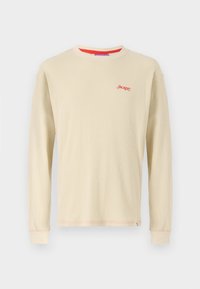 Long-sleeve beige ribbed T-shirt with red embroidered logo, contrasting orange neckline trim, small side tag, and fitted cuffs.