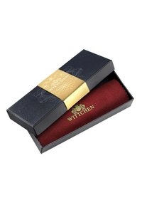 Oggetto in tessuto rosso testurizzato esposto in una scatola nera con una fascia oro e nera che presenta il logo "WITCHEN".