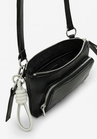 Schwarze Leder-Crossbody-Tasche mit zwei Reißverschlussfächern, ausgestattet mit silbernem Zubehör und einem weißen Lederakzent am Griff.