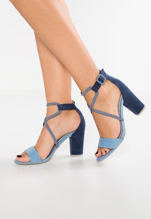 Blå hælede sandaler med en kombination af lys og mørk blå ruskind, åben tå-design og ankelrem med spænde-detalje.